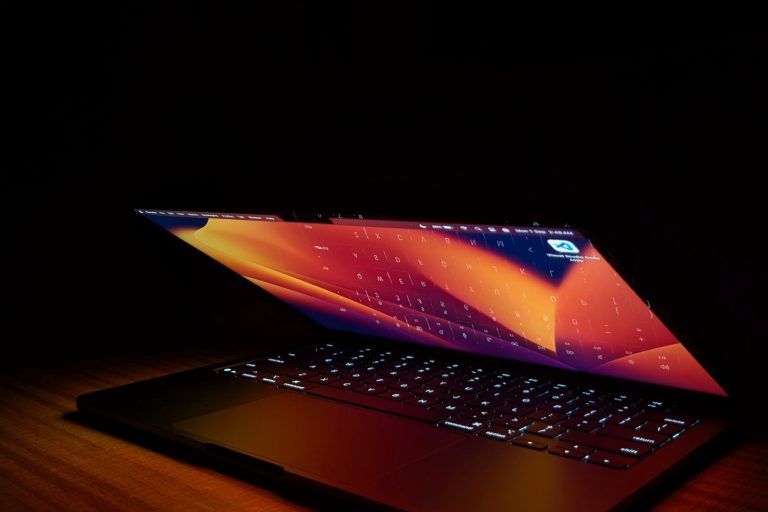 Otwarty laptop w ciemnym pokoju, jedynym światłem jest jego ekran
